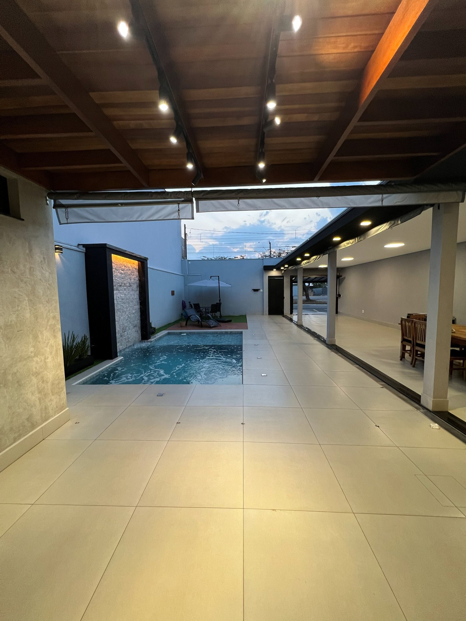 Vista da piscina iluminada e area gourmet a noite